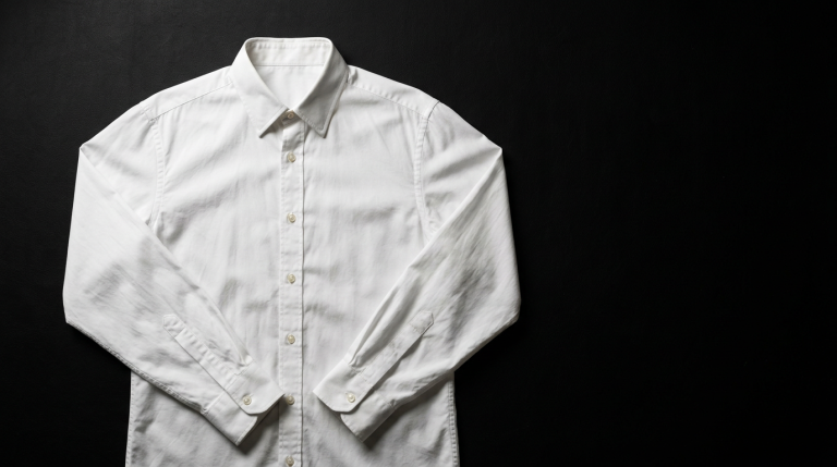 Crisp white COS cotton poplin button-down shirt laid flat on matte black background, editorial fashion photography