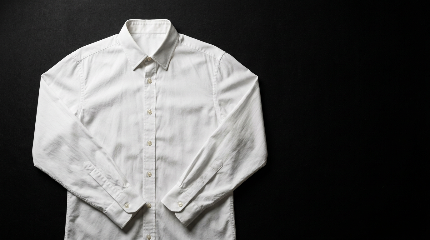 Crisp white COS cotton poplin button-down shirt laid flat on matte black background, editorial fashion photography
