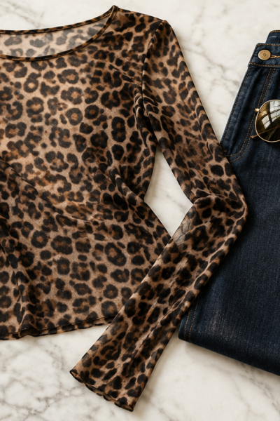 Leopard print mesh top, dark wash wide leg jeans, and oversized gold aviator sunglasses styled on white marble