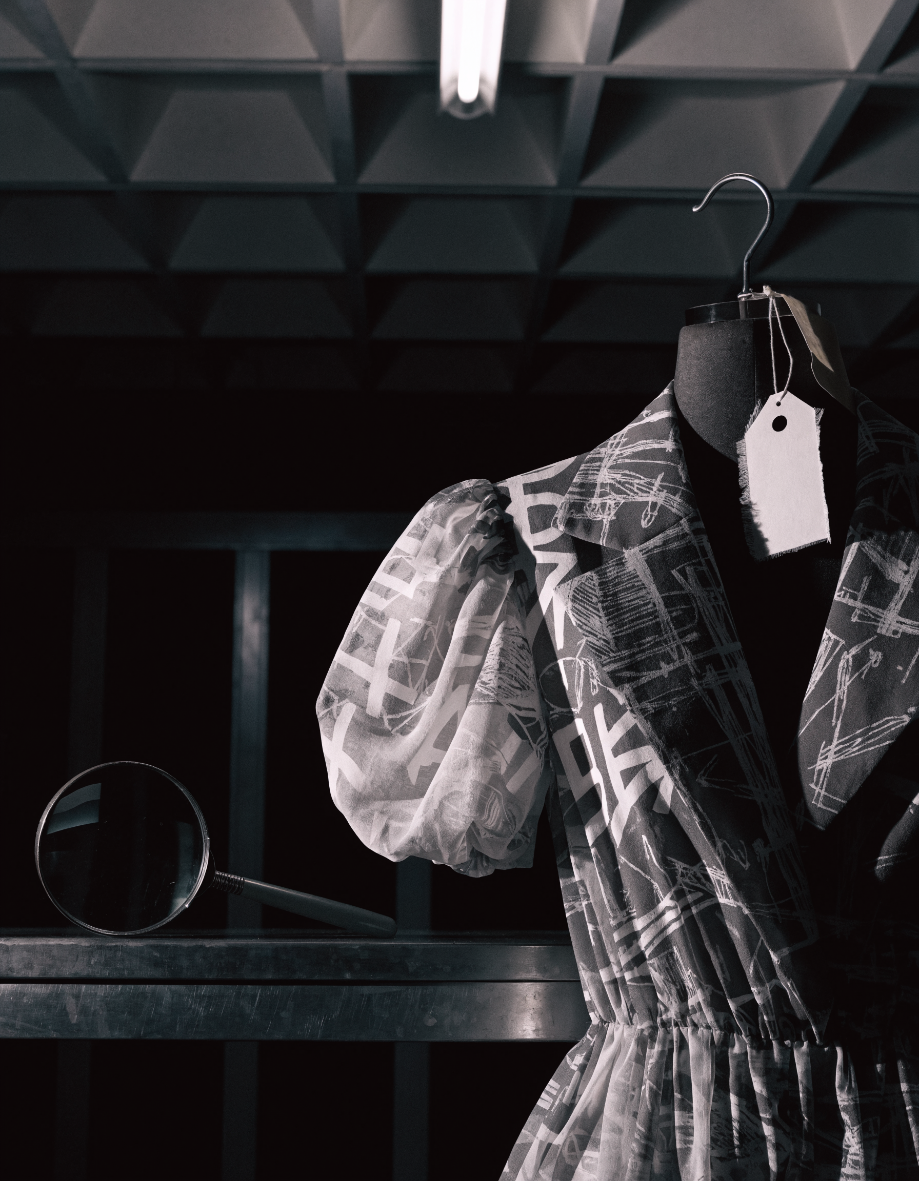 Over-printed midi dress on a dressmaker torso with an evidence tag and magnifying glass