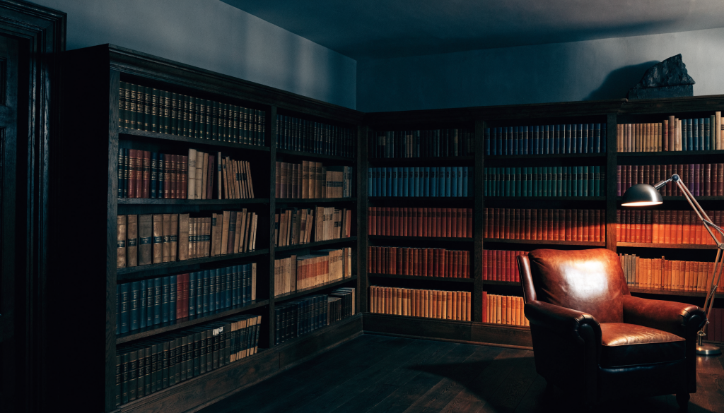 Grand home library with floor-to-ceiling shelves, a leather armchair and an amber reading lamp